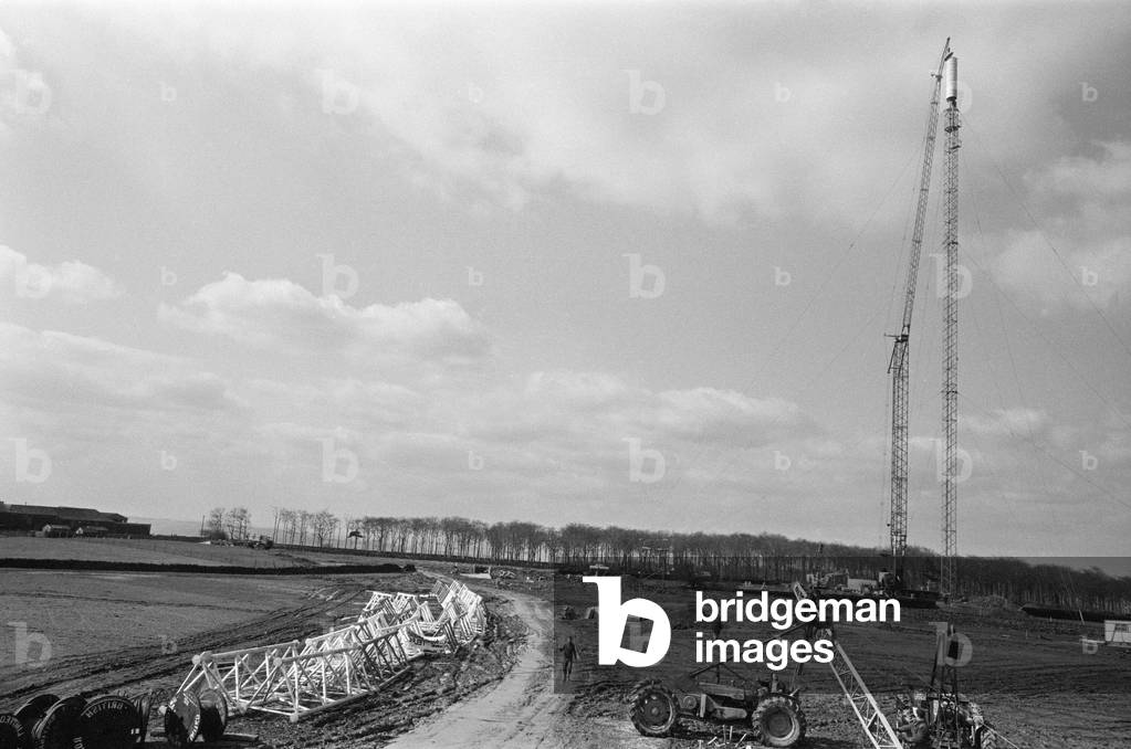 The collapsed Emley Moor transmitting station mast lies on the ground as engineers put the finishing touches to the BBC Two mast which towers 307ft off the ground. 16th April 1969 (b/w photo)