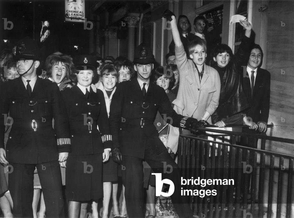 Fans of The Beatles pictured behind Police Officers outside the London Palladium, where the group are performing this evening on BBC-TV's `Sunday Night at the London Palladium' 13th October 1963.