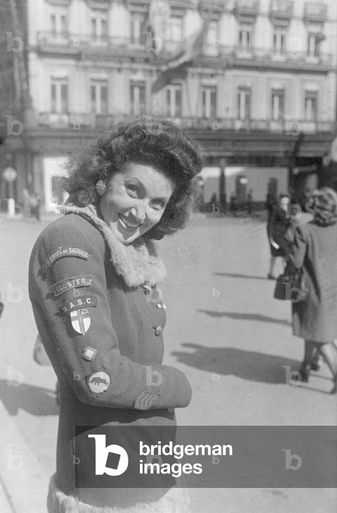 A Brussels girl whose hobby is collecting badges from the liberating Allied troops, shows off her collection on the sleeve of her coat during the Second World War, September 1944 (b/w photo)