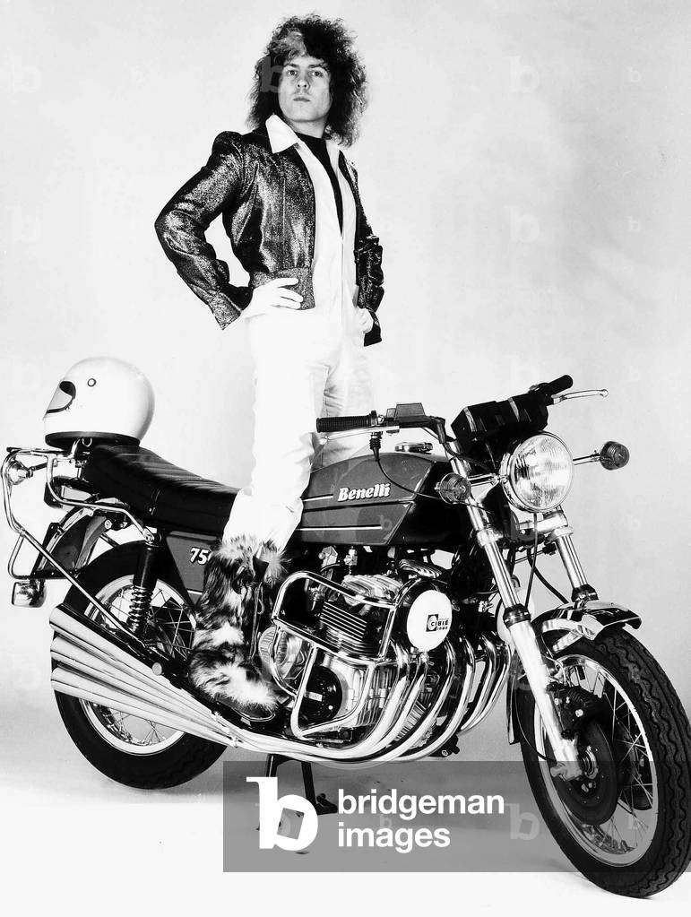 Marc Bolan singer standing on motorcycle - 1976