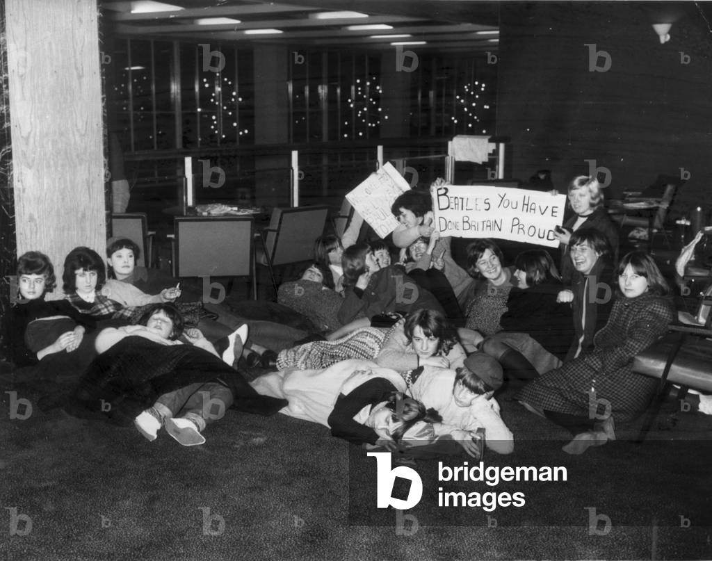 Beatles fans crowd the Queens Building Lobby at London Heathrow Airport in anticipation of their heroes' return Saturday 22nd February 1964.