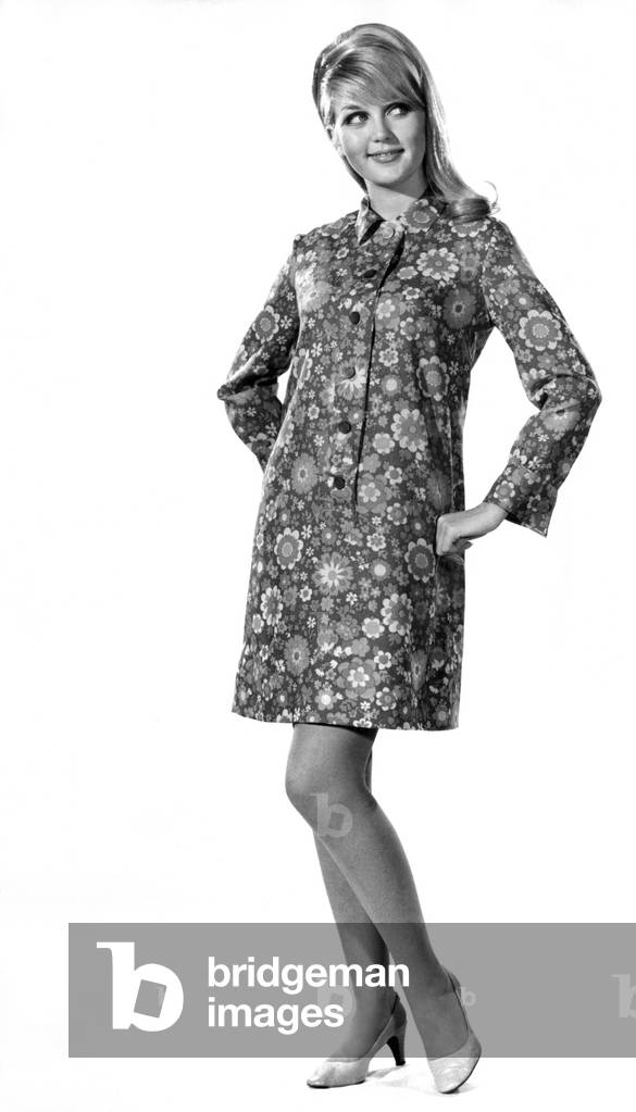 This classic shirt-dress has a superbly slim-line front band.The crisp collar and wide cuff give it that slick look. This dress is clearly designed to flatter any figure. Our original is made in vivid floral-printed wool. January 1968