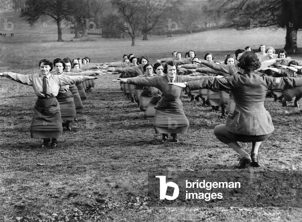 World War II. Women. Keep fit. The knees double bend is not so easy, as it appears, in the service skirt but the recruits gallantly get down to it in an A.T.S. camp attached to the Western Command. Feb 1940