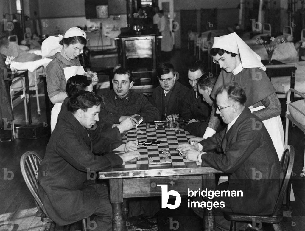 Sister Shine (right) and nurse Cockin playing cards with a group of boys in blue.