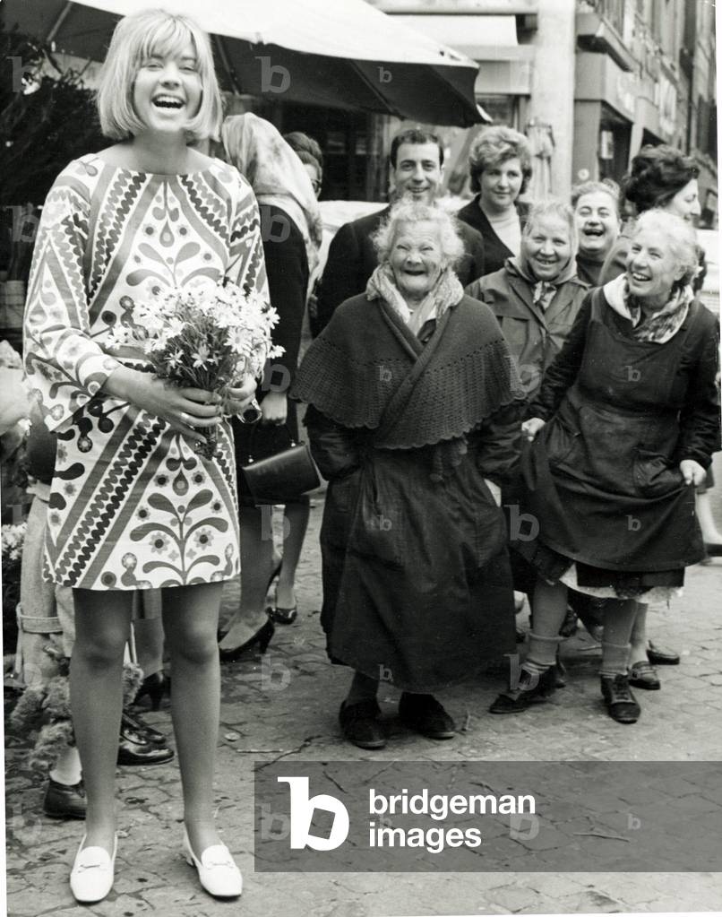 Trisha Locke wearing a short skirt in Rome, Italy seen with local flower sellers, 1960 (b/w photo)