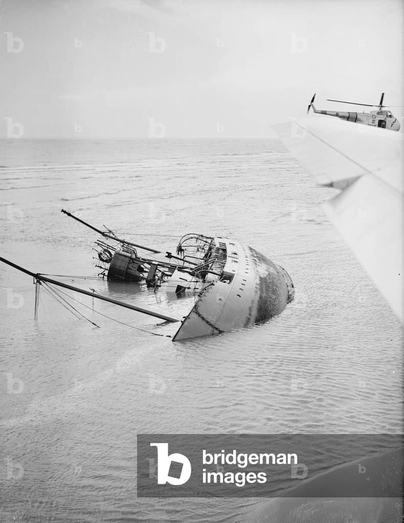 A USAF Search and Rescue helicopter from RAF Manston prepares to land a search party from Trinity House on the Goodwin Sands in the English Channel 29th November 1954 (b/w photo)