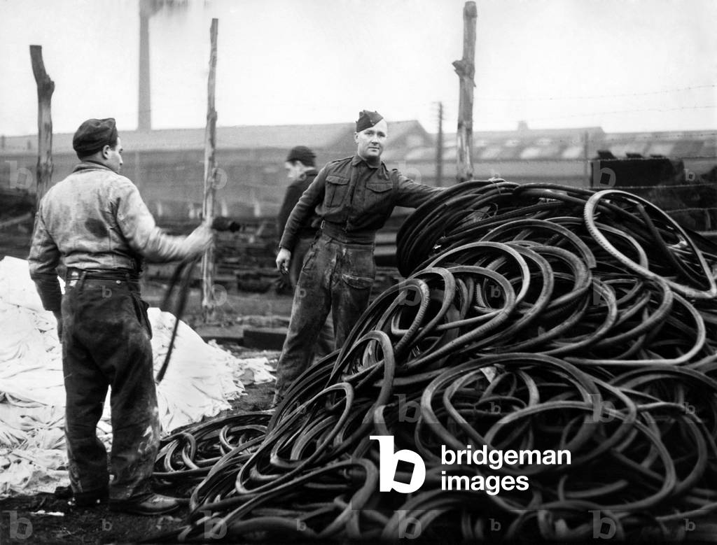 The war on Waste seen here at a Western Command Salvage Depot. Men from the yard inspect cycle salvaged tyres piling up. January 1943