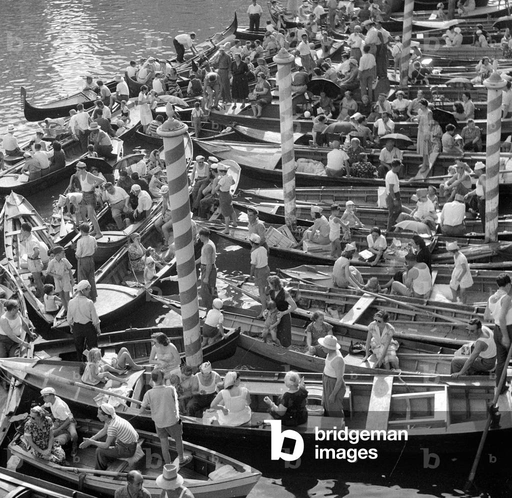 Boats and gondolas tied up as the procession of gondolas pass along the Grand Canal Venice September 1952 (b/w photo)
