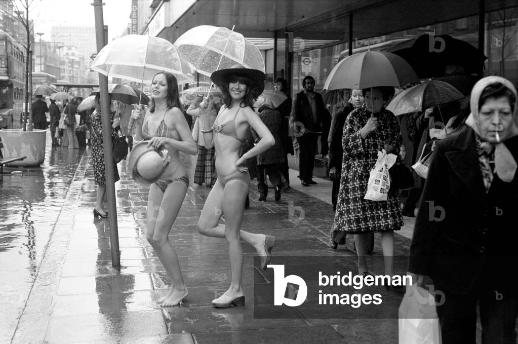 Models Wendy and Jackie seen here modelling the latest in swimwear on a wet Oxford Street, April 1975 (b/w photo)