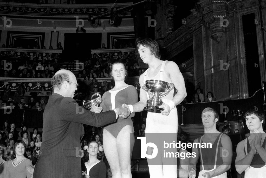 National Gymnastics Tournament at The Royal Albert Hall: L/R The Overall Winner Avril Lennox, Mr. Michael Christiansen, Editor of the Daily Mirror, and Overall Winner Tommy Wilson pictured with winning Cups at the Royal Albert Hall on the 18th of January, 1975. January 1975
