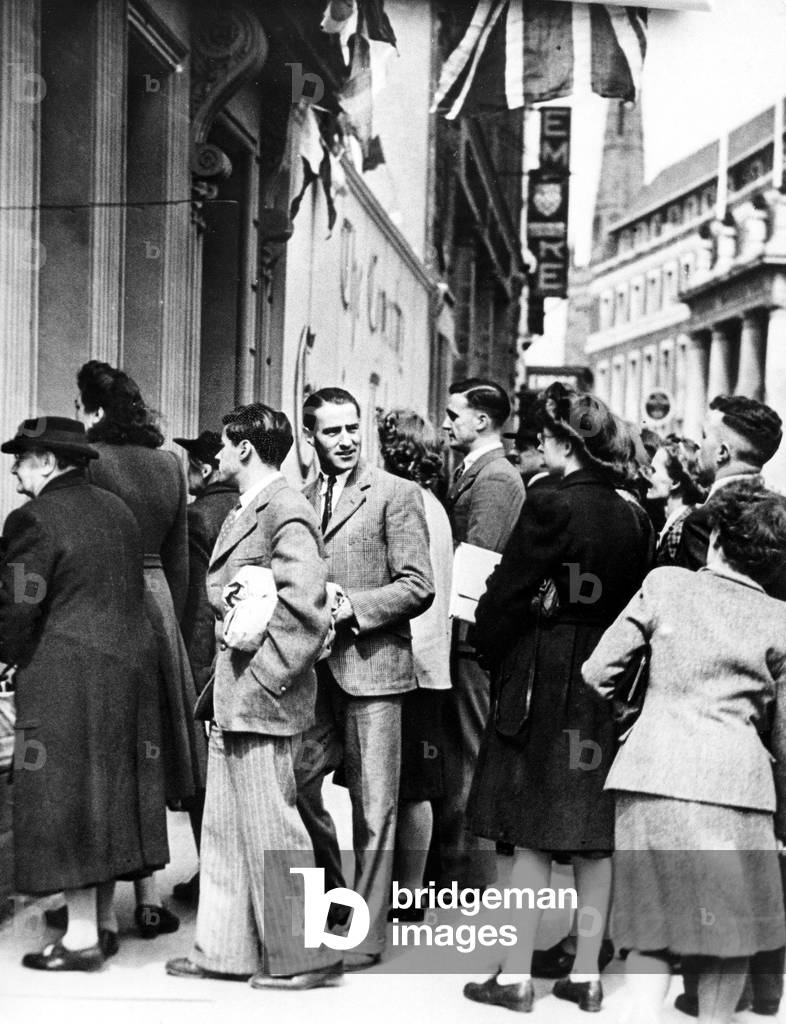 Coventry Evening Telegraph readers queue at the Hertford Street offices of the paper, to read the German surrender news in the window, 3pm, 7th May 1945 (b/w photo)