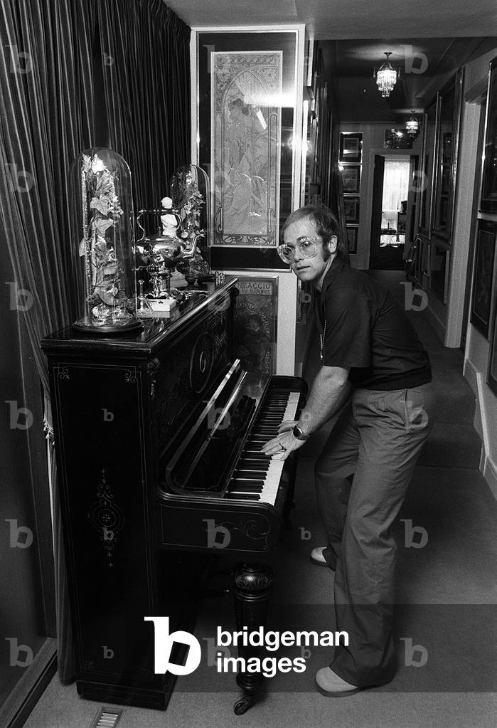 Sir Elton John in his new £50,000 mansion in Camberley, Surrey, laying his upright piano, June 1974