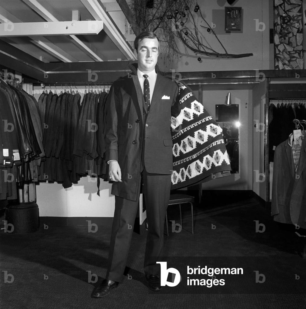 Male model wearing raincoat in menswear department, 1966 (b/w photo)