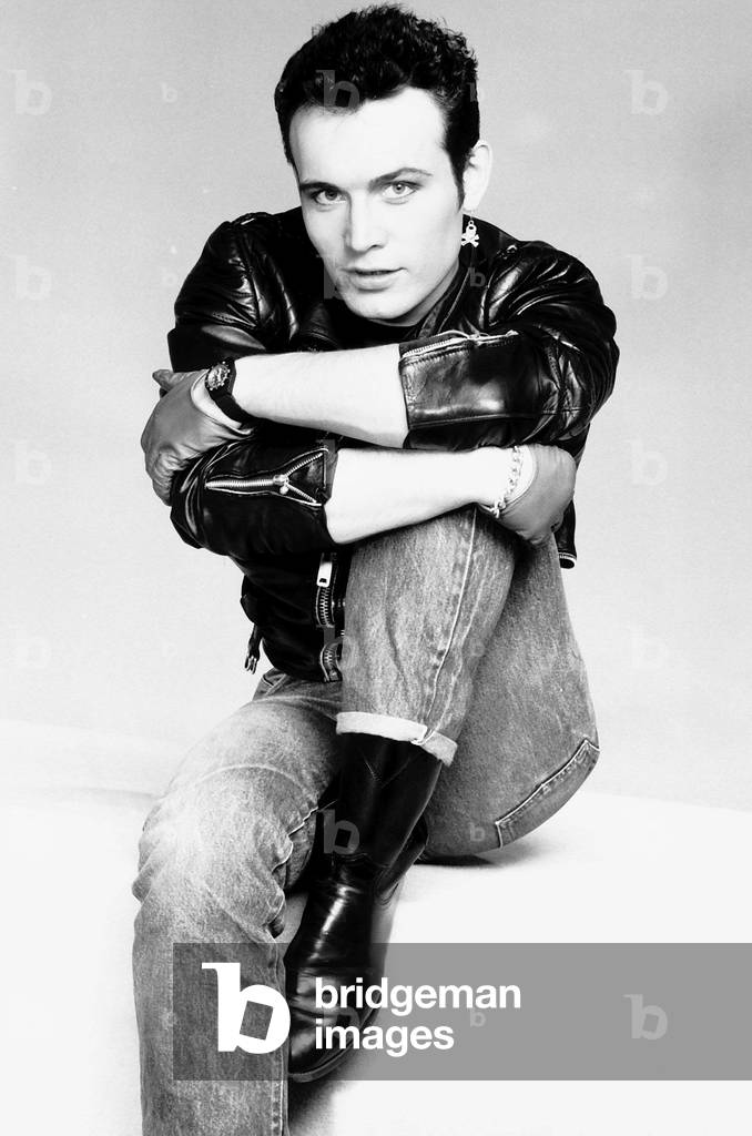 Adam Ant pop singer arms round leg jeans leather jacket 
Circa 1980