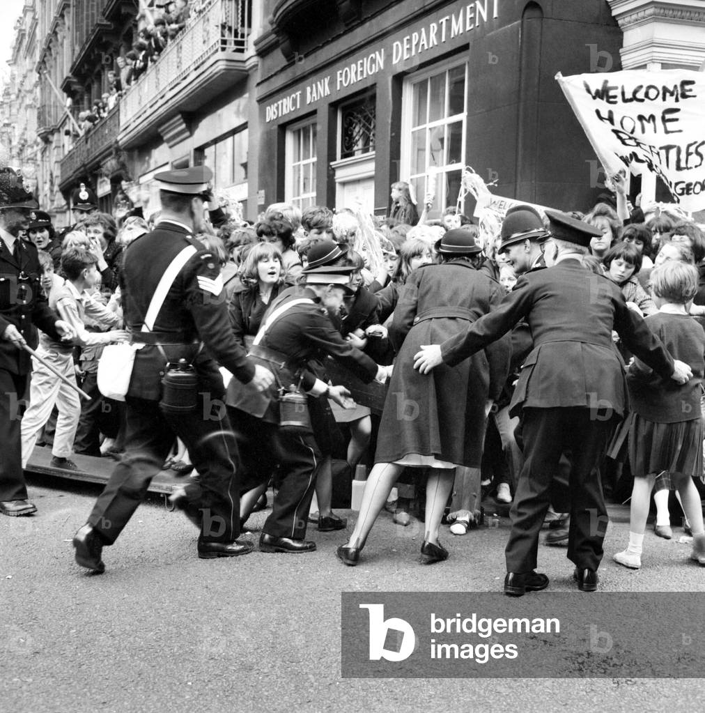 Police try to control fans in the streets of Liverpool before the premiere of the Beatles film 'A Hard Day's Night'. 
July 1964