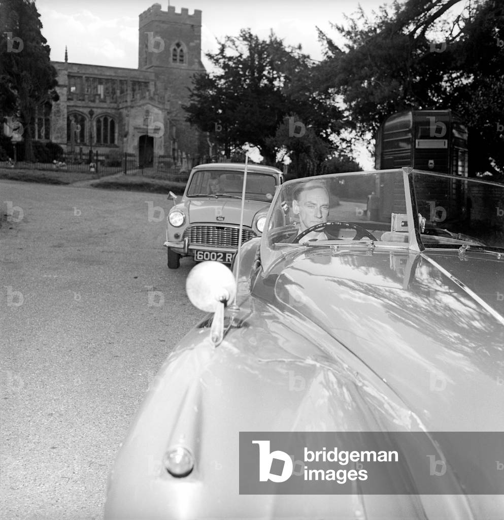 Inventor Jim Pickering seen here behind the wheel of his jaguar sports car which has been fitted with the periscope parking mirror, 1964 (b/w photo)