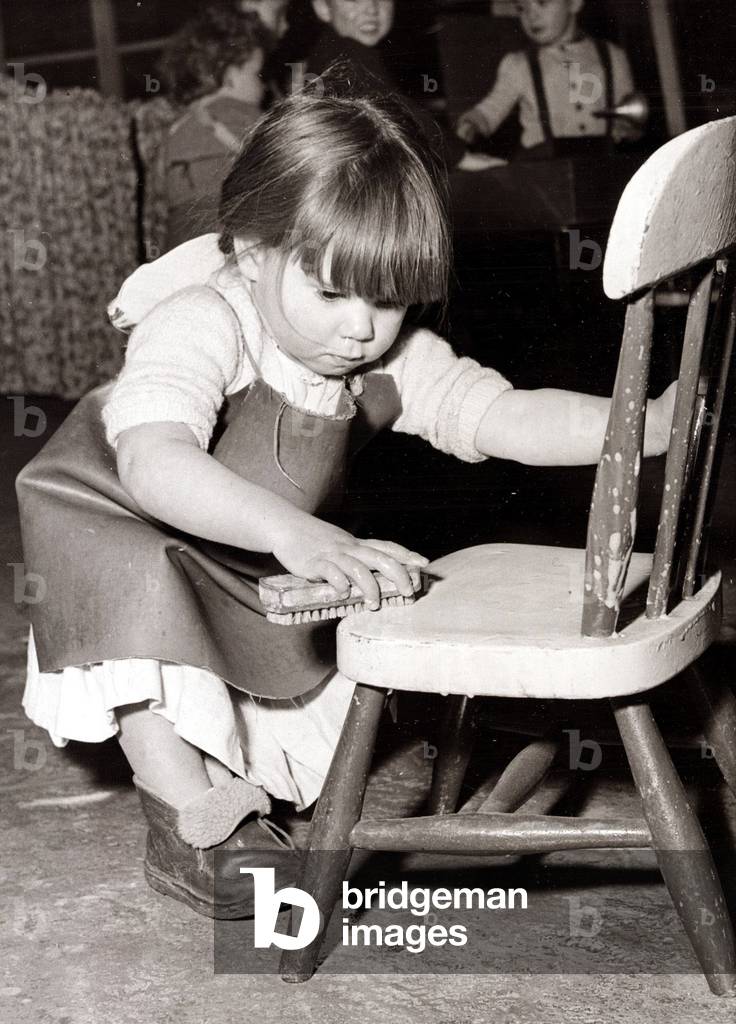Little girl cleaning a chair, c. 1960 (b/w photo)