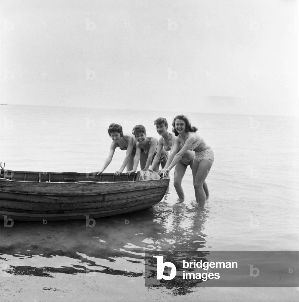 Bathing Girl: Glamour on the Clacton Beach: L. to R. Peggy Palmer, 16, Waitress Clacton; Maureen Kenn, 21, Waitress Clacton; Barbara Jollies, 21, Red Coat Ilford; Sherral Mason, 19, Red Coat Blackpool pushing the boat out. June 1960