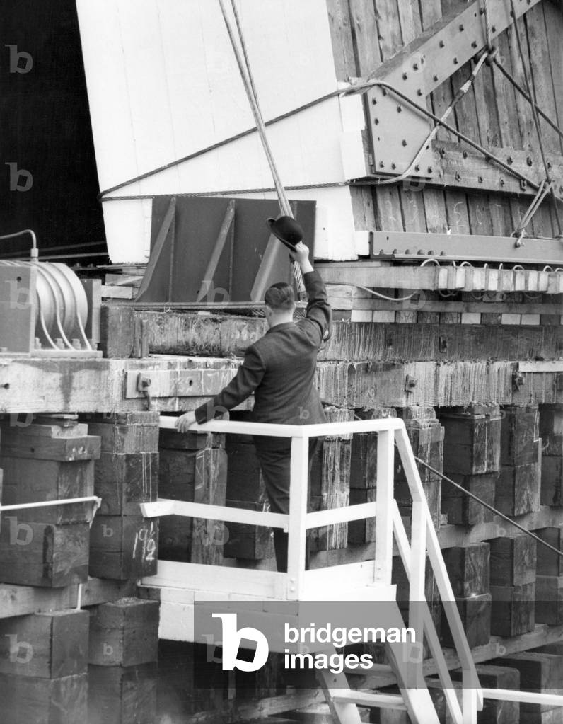 Shipyard director George Parker rose to the occasion when the new liner Queen Elizabeth II seemed reluctant to be launched. He gave her a shove and a second later the Cunarder slid down the stocks from John Brown's ship yard into the River Clyde. It was a symbolic gesture, and brought a hilarious ending to the few seconds during which the new QE2 seemed reluctant to move. Nothing happened after the Queen had pressed the button to release the launching gear. 20th September 1967 (b/w photo)