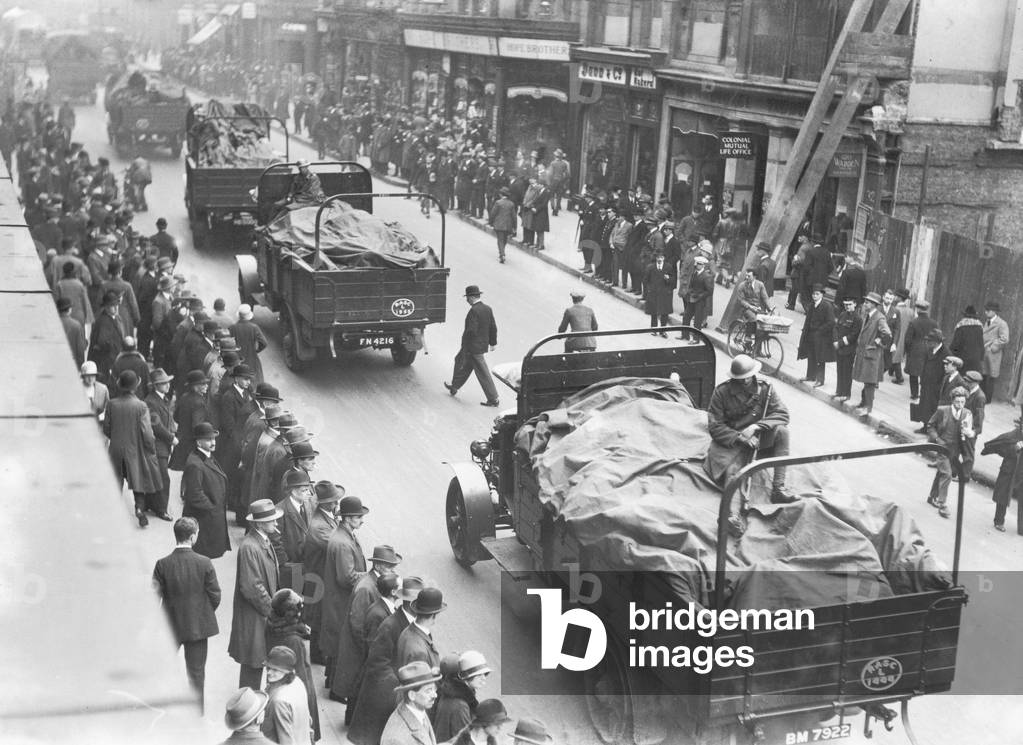 Soldiers ride shotgun as a food convoy passes through central London, on the 9th day of the General Strike. The national dispute came about after negotiations between the miners and mine owners failed over wages and the strike began on 3 May 1926. Millions obeyed the strike call, bringing transport systems to a halt while newspapers were not printed. The government responding by using volunteers to run trains and buses and sent in troops to move supplies from the London docks. There were clashes between police and crowds in many areas and at least 4000 strikers were arrested. There were attacks on buses and trains, including the derailing of the Flying Scotsman. The strike was called off unilaterally by the TUC on 12 May with no guarantees of fair treatment for the miners who fought on to bitter defeat in October. 11th May 1926 (b/w photo)