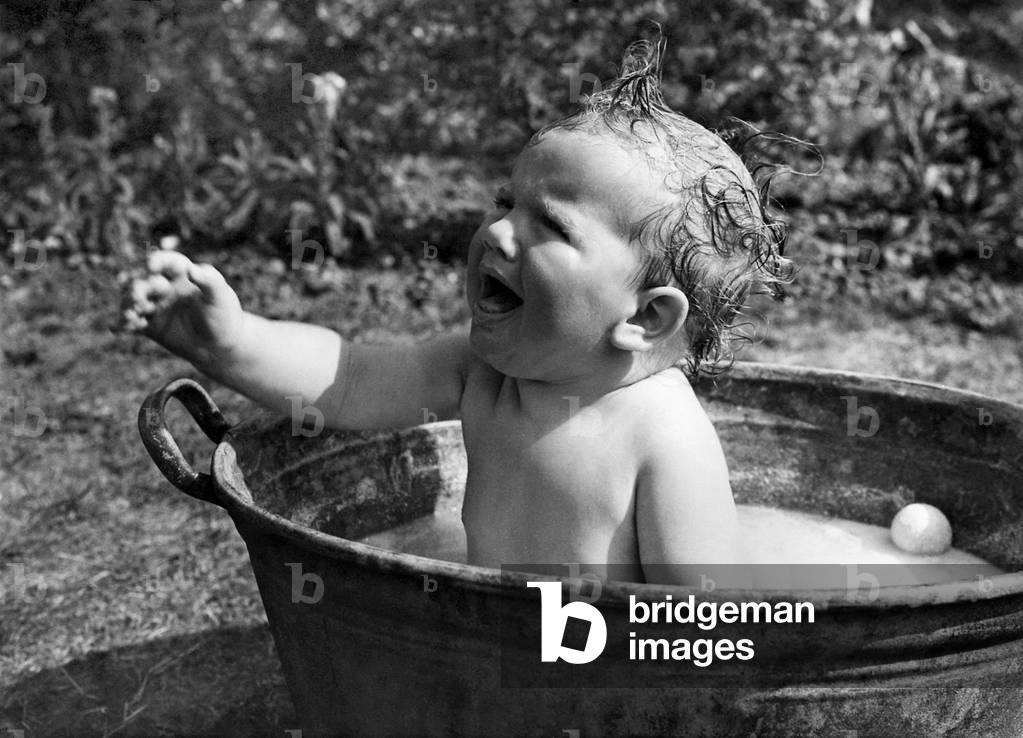 Young toddler having a wash in a tin bath in the back garden in Erith, Kent. 
July 1943