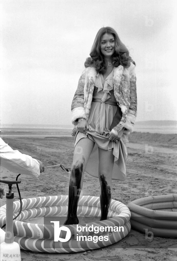 New detergent for removal of oil publicity stunt. Miss U.K. Helen Morgan demonstrates with oil on her legs, and has it removed by the detergent, March 1975(b/w photo)