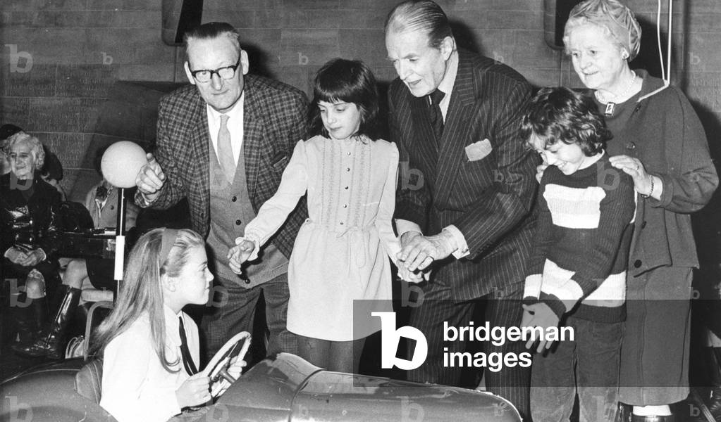 Jack Warner, who played Dixon of Dock Green demonstrates correct Zebra crossing procedure to youngsters Graeme Bland and Lois Savage, both of West Jesmond School and in the car Gilliam Rutherford of Preston Grange School, circa 01/06/1975 (b/w photo)