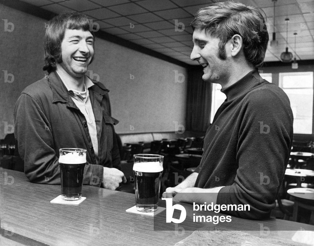 Two men have a pint of beer and a gossip at the bar