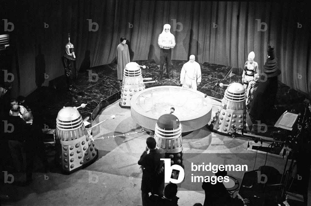Mission to the Unknown', the second story of Season 3 of Doctor Who. The Beasts from UGH (United Galactic Headquarters), hold a secret meeting. A resolution was unanimously passed by the great powers of the Outer Galaxies that earth should be totally destroyed. The Beasts from UGH are seen gathered round the debating table. 6th August 1965 (b/w photo)