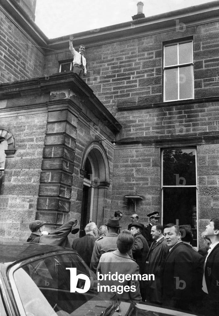 World Champion Walter McGowan on the roof of his home waves his thanks to the local fans who came out to welcome him home, June 1966 (b/w photo)