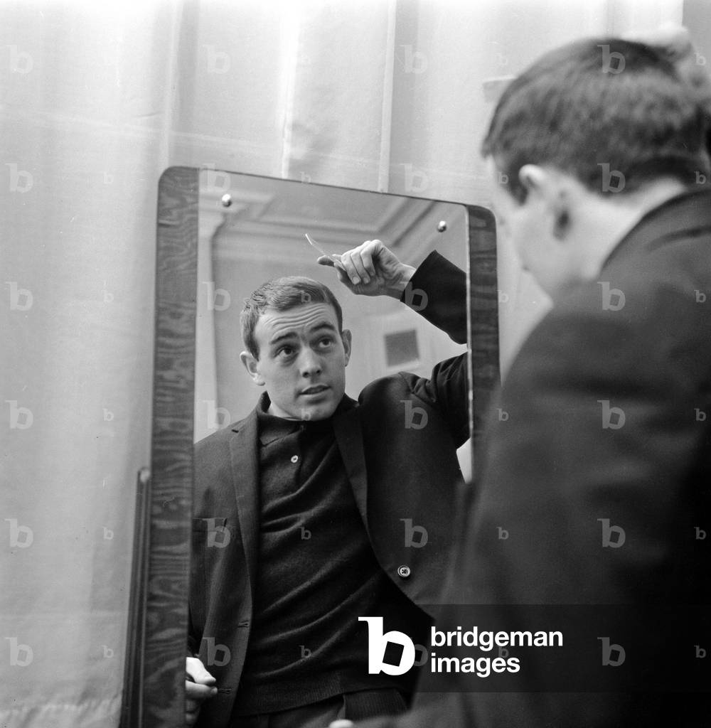 Liverpool player Ian St John looks in the mirror to comb his hair as he gets ready for dinner in his London hotel room the night before their FA Cup match against Arsenal at Highbury. Liverpool won the game 0-1. 14th February 1964 (photo)