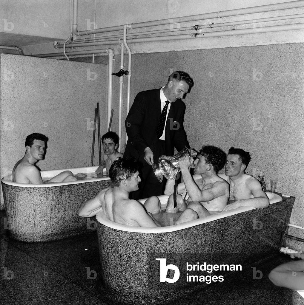 Tottenham Hotspur Double Winnkng Season 1960 - 1961. A Spurs player drinks from the FA Cup trophy as he sits in the bath following their victory over Leicester City in the Final, clinching an historic double. Watching is Spurs manager Bill Nicholson. 6th May 1961 (photo)