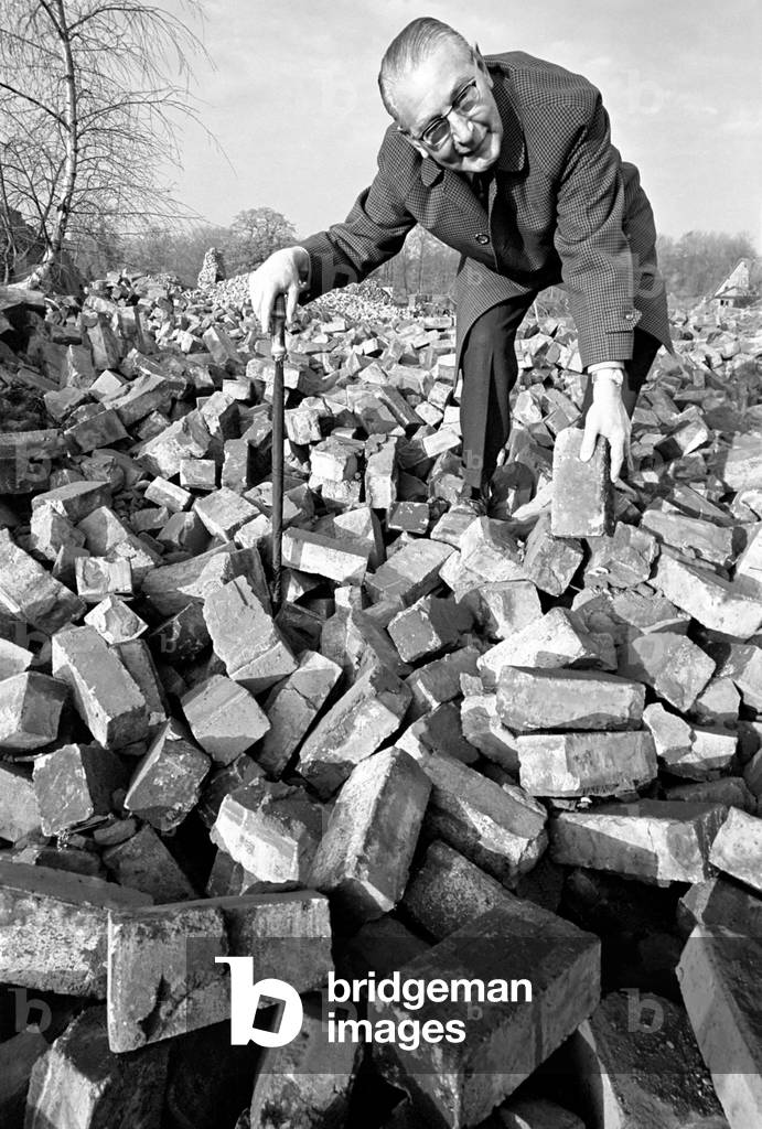 People - elderly. An old man searching through a pile of bricks. December 1969