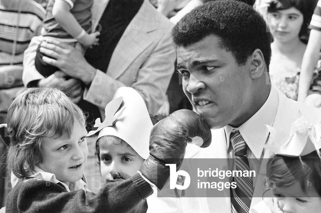 World heavyweight boxing champion Muhammad Ali presented a sunshine coach on the behalf of the Variety club of Great Britain, the children's charity organisation, to the hospital for sick children, Great Ormond Street. 11th August 1977 (b/w photo)