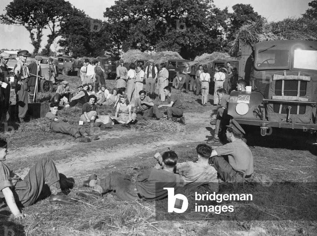 Soldiers and land army girls take a rest for a cup of tea during a harvest in East Anglia, 4th September 1942 (b/w photo)