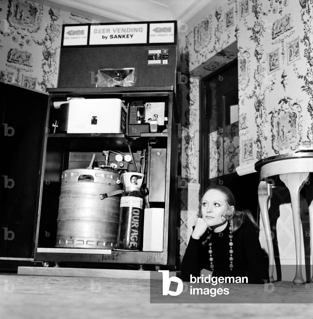 Inventions: Britain's first automatic refrigerated draught beer vending machine was demonstrated by the Brewery Division of GKN Sankey Ltd., of Bilston Staffs, at Quaglino's Bury Street, London. Woman with the front of the autobarmaid open showing the interior. December 1969