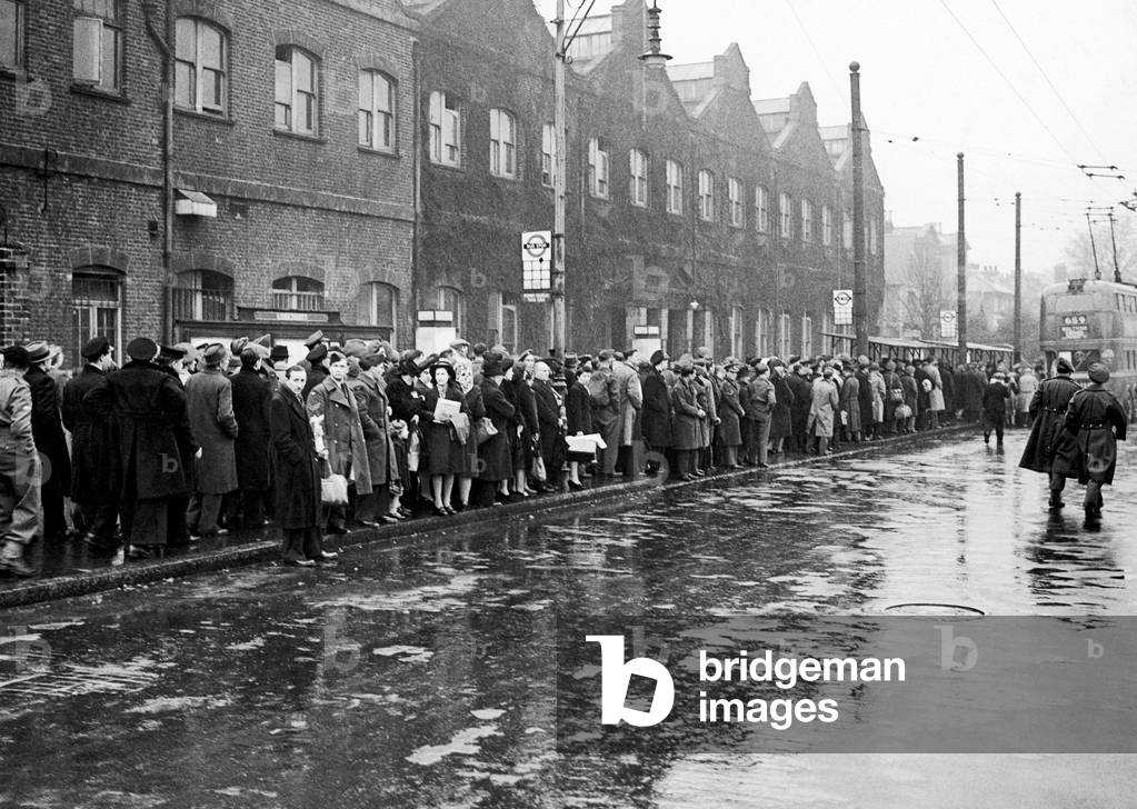 The queue to get home- While Ma has been queuing all morning to get dinner, Pa and the children are queuing to get home to it in this scene outside a suburban tube station, c. 1946 (b/w photo)
