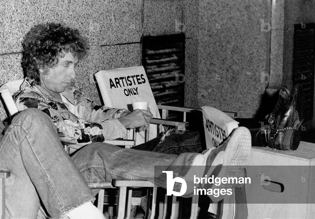 Bob Dylan American singer songwriter with his feet up on a film set for Hearts of Desire in which he stars September 1986 (b/w photo)