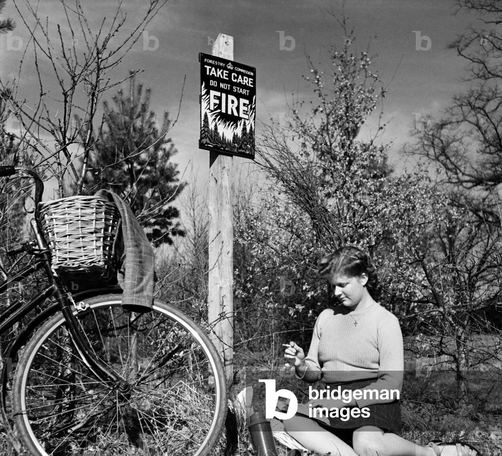 Woman relaxes with a book next to her bicycle next to a 