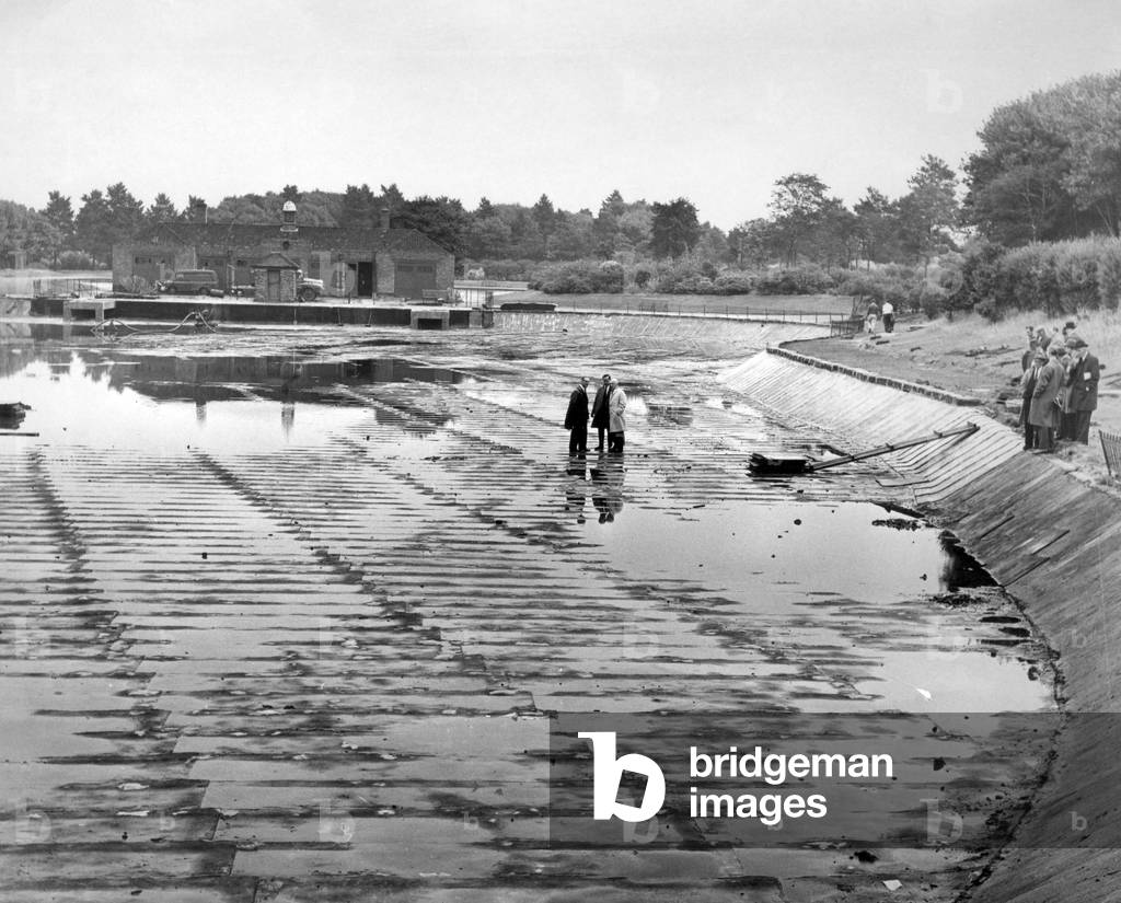 Walton Hall Park in Walton, Liverpool, a 130-acre park, opened to the public in 1934. Pictured, attempt to make the Boating Lake watertight, by laying half inch slabs of a bitument material mixed with fibreglass and wire netting, in the past a mysterious leak has continually drained it. 26th August 1965 (b/w photo)