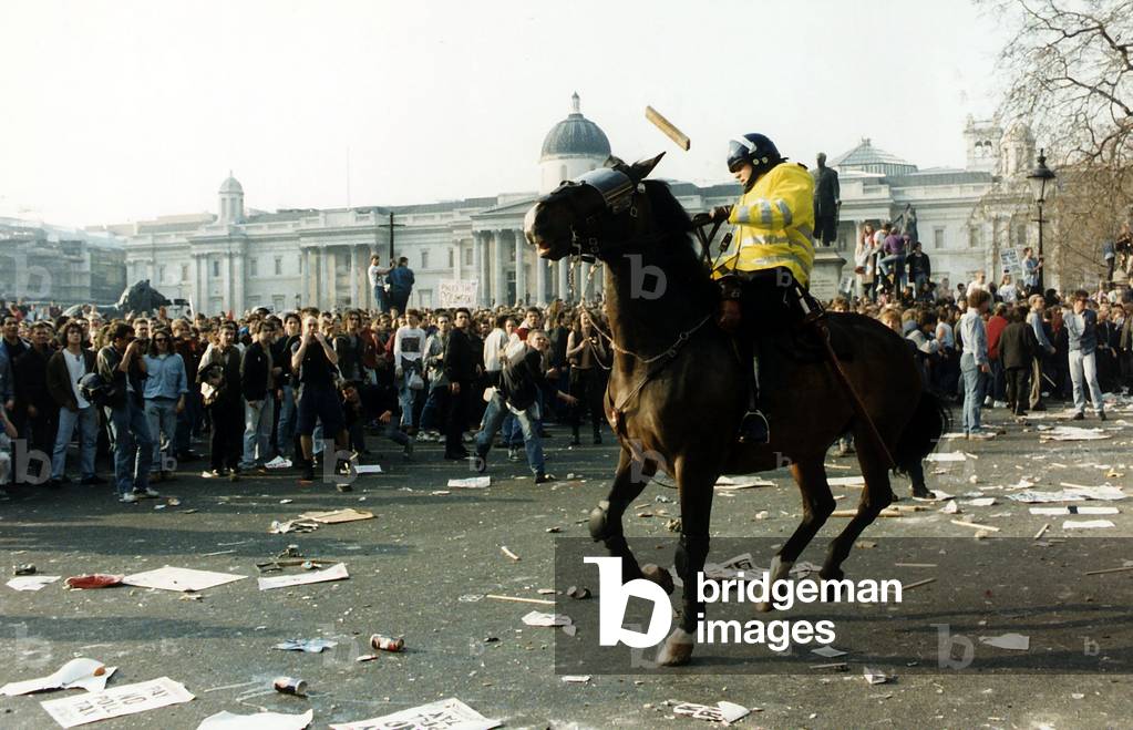 A demonstrator throws a piece of wood at a police officer on horseback, during a demonstration against poll tax, Trafalgar Square, March 1990 (photo)