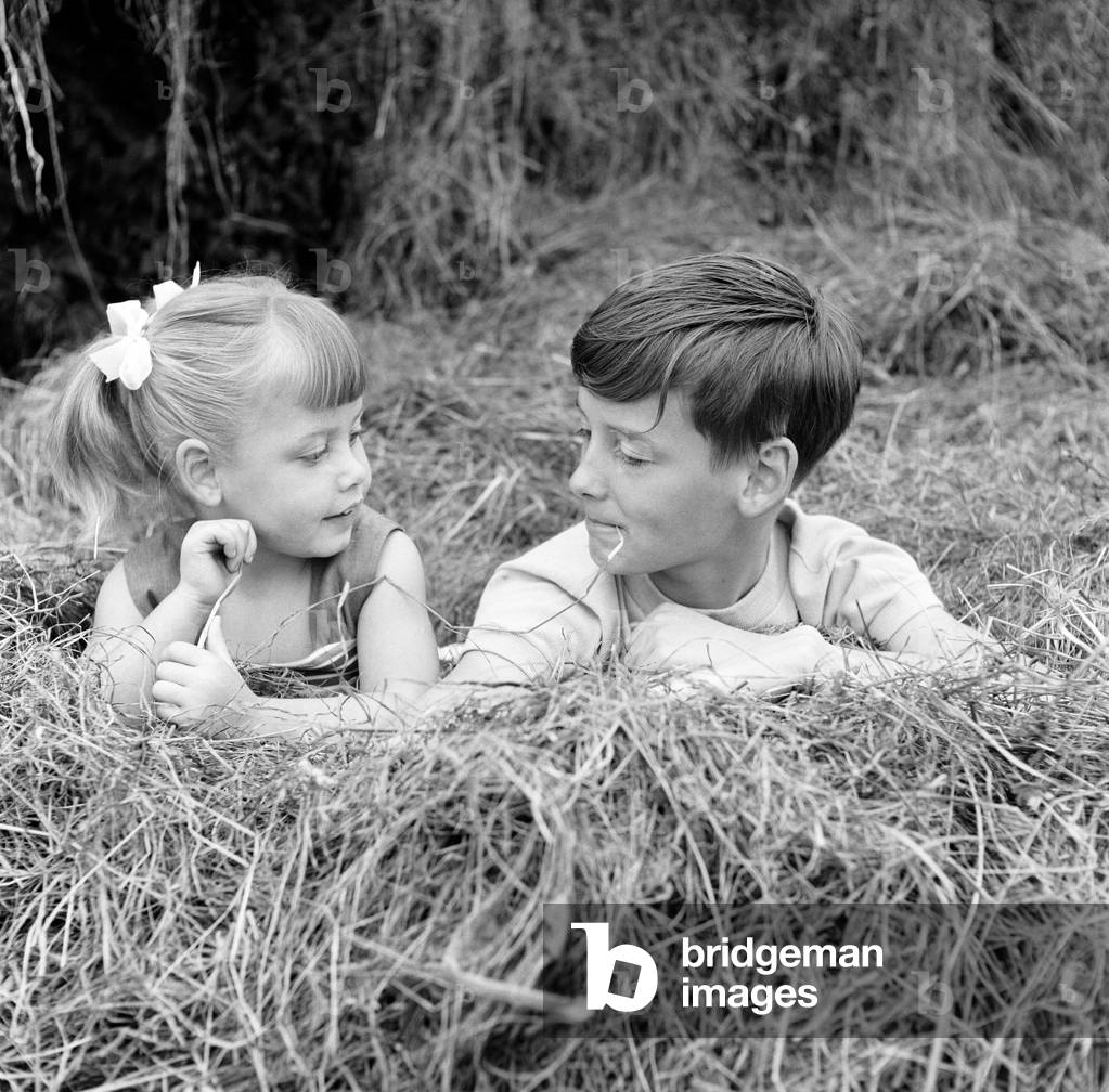 Siblings, Helen (3) and Paul Burrows (9) from Waterloo, London, enjoy their first day in the countryside at a farm in Chipperfield, Herts, 7th September 1956 (b/w photo)