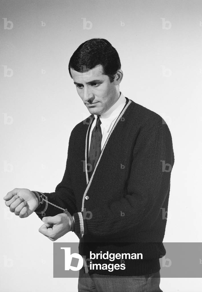 Model Henry Fern in cardigan wearing handcuffs, c.1964 (b/w photo)