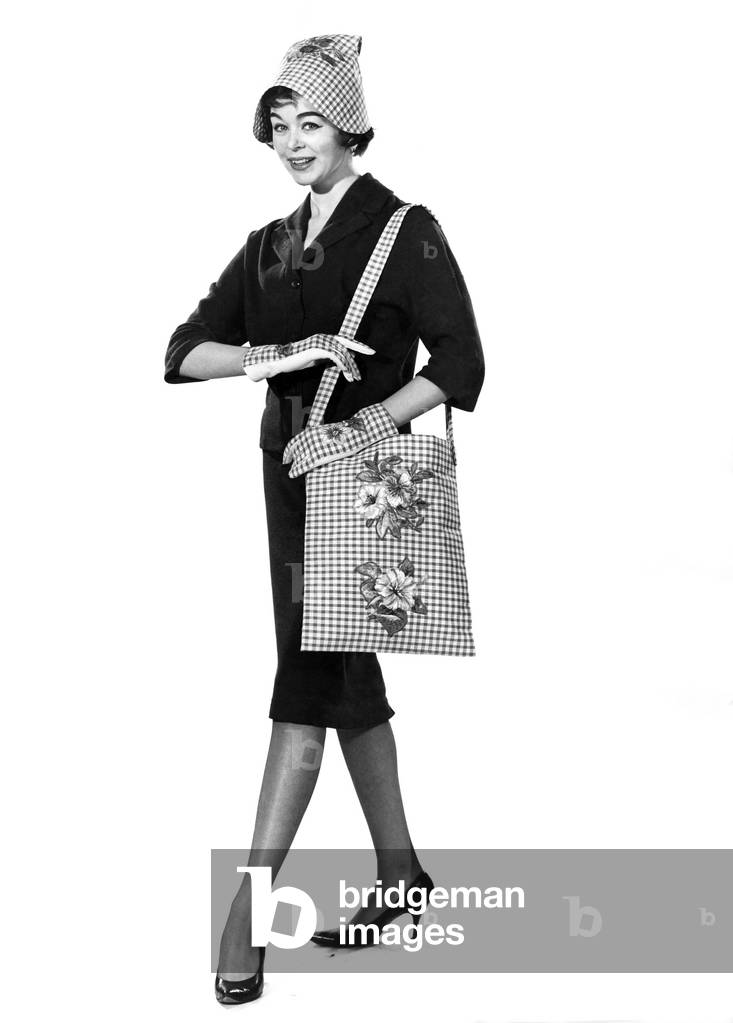 Reveille Fashions: Jackie Jackson modelling matching hat, gloves and shoulder bag, March 1960 (b/w photo)