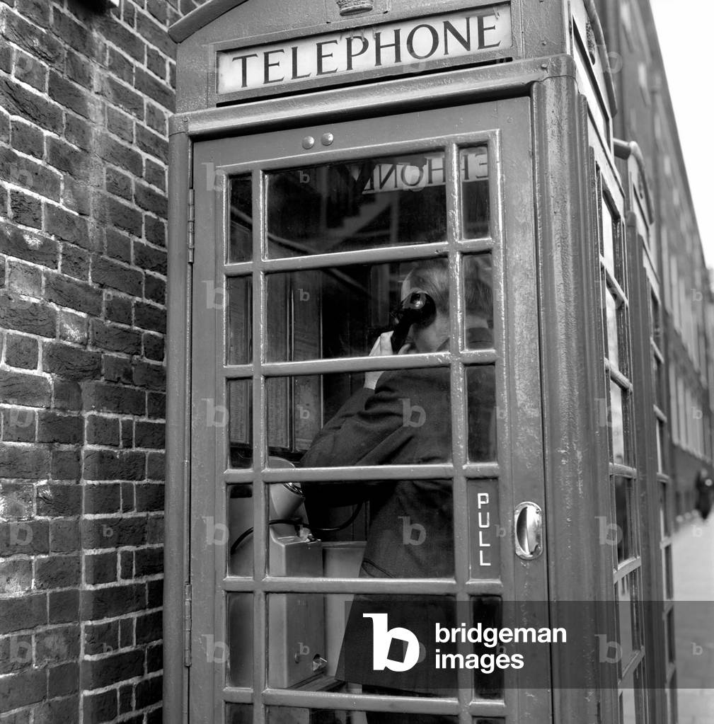 Man using a telephone box, April 1975 (b/w photo)