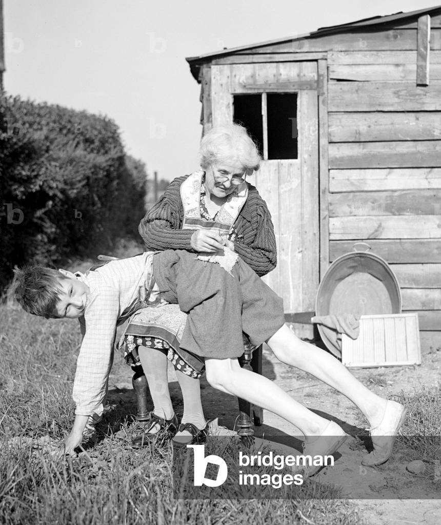 Old lady sewing boys pants, 1945 (b/w photo)