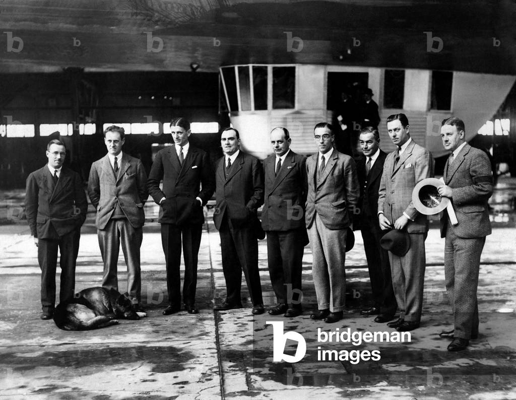 The men who built and will control the airship R101, seen here at the Royal Airship Works Cardington, Bedfordshire. 
l-r Flight-Officer Maurice H. Steff , Noel Graboswky-Atherstone (Lt Cdr.), Herbert C Irwin, Flight Lieutenant, (Captain of R101), Lt Col Vincent Richmond, Major George.H.Scott 
Assistant Director of Airship Development, Mr DSD Collins, Mr B Fitzgerald, Lt S Nixon and Commander W.H Watt.

They are pictured before one of the early trial flights in October 1929. 
After extensive modifications on the evening of 4th October 1930 the R101 left Cardington. She carried 42 crew, 6 officials and 6 passengers. A crowd of over 3,000 came to watch the departure. The start of the journey did not go wells; ballast had to be dumped to compensate for over loading, strong winds were encountered and the aft engines broke down.

At approximately 2 am the R101 passed over Beauvais, a French city to the north-west of Paris. Already flying at very low altitude she went into a dive and despite all the efforts of the crew she crashed just south of the city. The airship ran along the ground for some distance before being engulfed by flames. 

October 1929