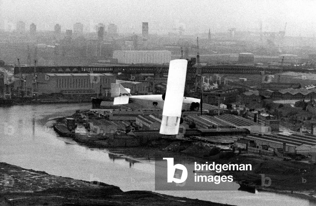 Wearside pilot Les Richardson flies his Currie Wot 1930s British single-seat aerobatic biplane aircraft over the River Wear in Sunderland, c. 14/06/1980 (b/w photo)
