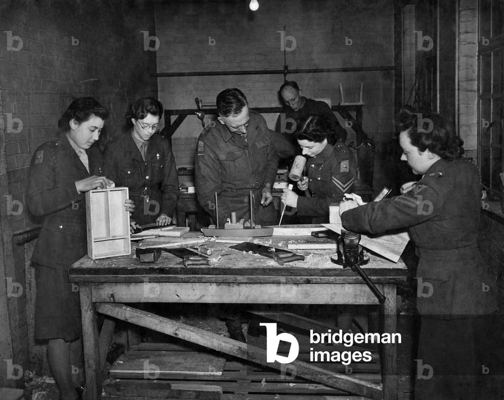 A.T.S. furniture factory. Lt. Archard (Centre) teaching his class the art of woodworking in the disused Police station. March 1944