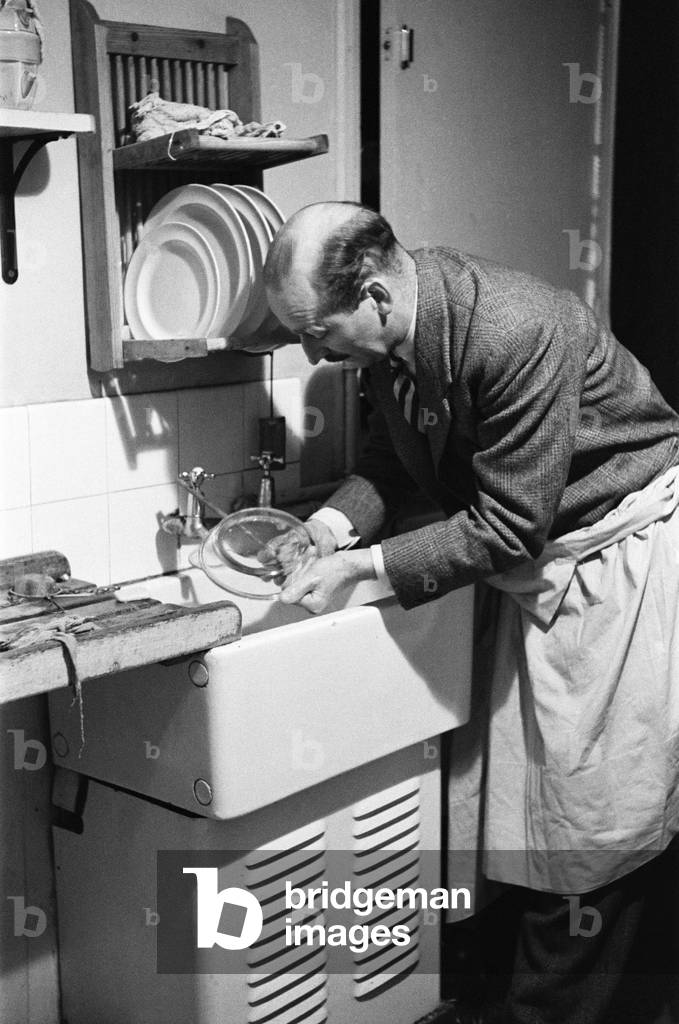 Ted Castle, the husband of Barbara Castle, doing the washing up at the kitchen sink, c. 1947 (b/w photo)